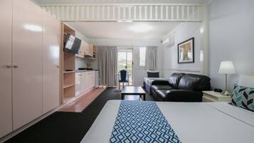 A hotel room with a bed, a sofa, a desk, a TV, and a window.