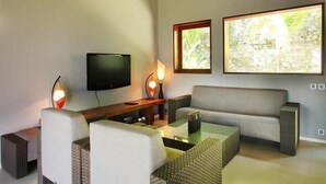 A modern living room with a flat-screen TV, a sofa, two armchairs, a coffee table, and two floor lamps. - Villa Tiara Lombok Island (Senggigi)
