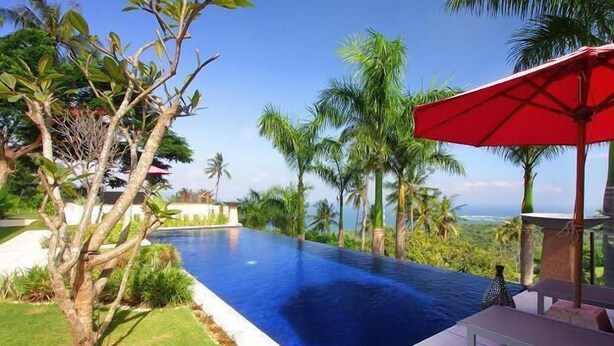 A swimming pool with a view of palm trees and a distant landscape. - Villa Tiara Lombok Island (Senggigi)