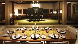 A dining area with a long table set for a meal, surrounded by chairs, with a stage in the background. - Villa Tiara Lombok Island (Senggigi)