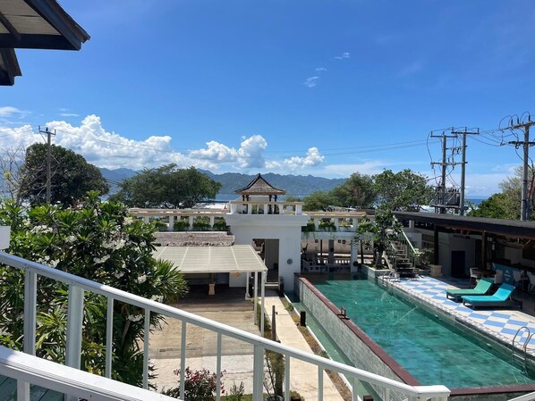 A hotel with a swimming pool, a covered area, and a view of mountains. - The Trawangan Resort (Gili Trawangan)
