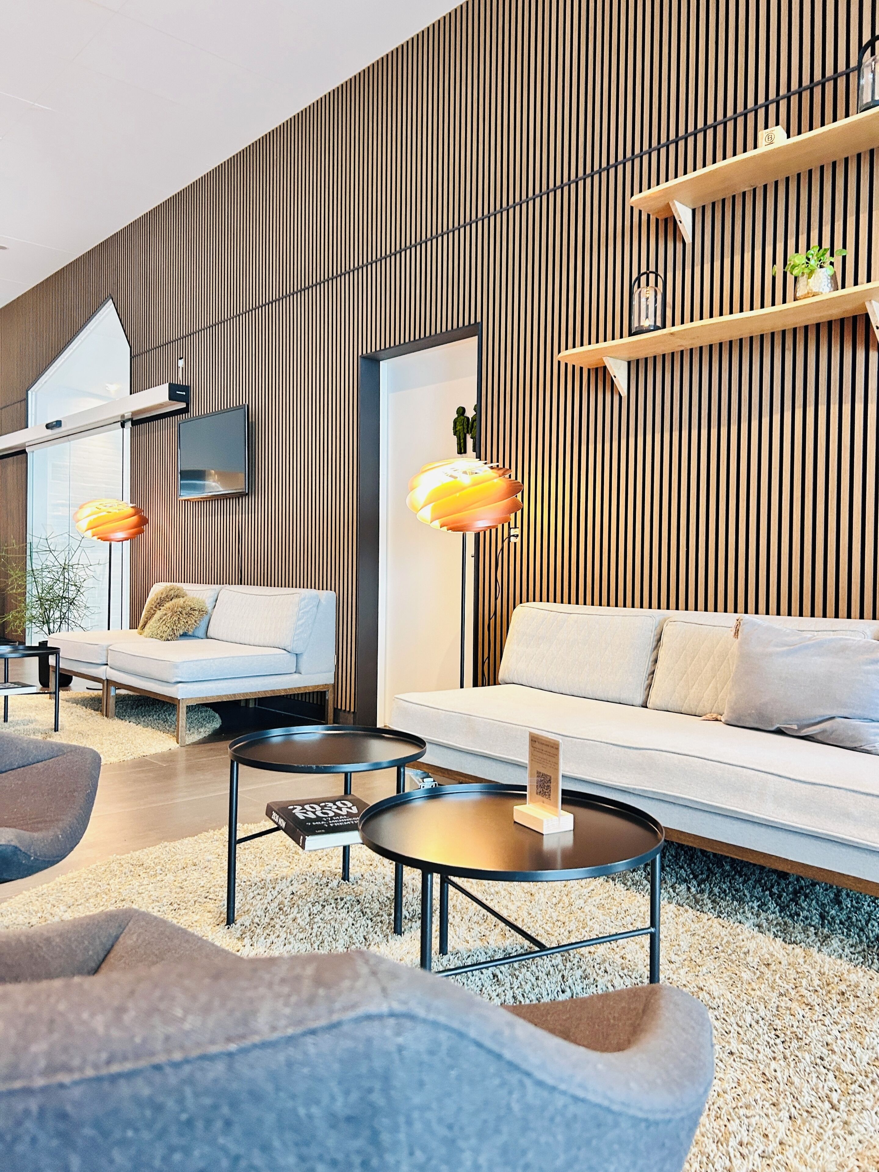 A modern living room with a sofa, two armchairs, a coffee table, and a TV mounted on the wall.