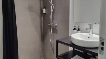 Un baño moderno con ducha, lavamanos y espejo.