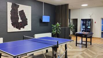 Enjoy ping pong and foosball in our modern game room with a flat-screen TV and comfortable seating areas.