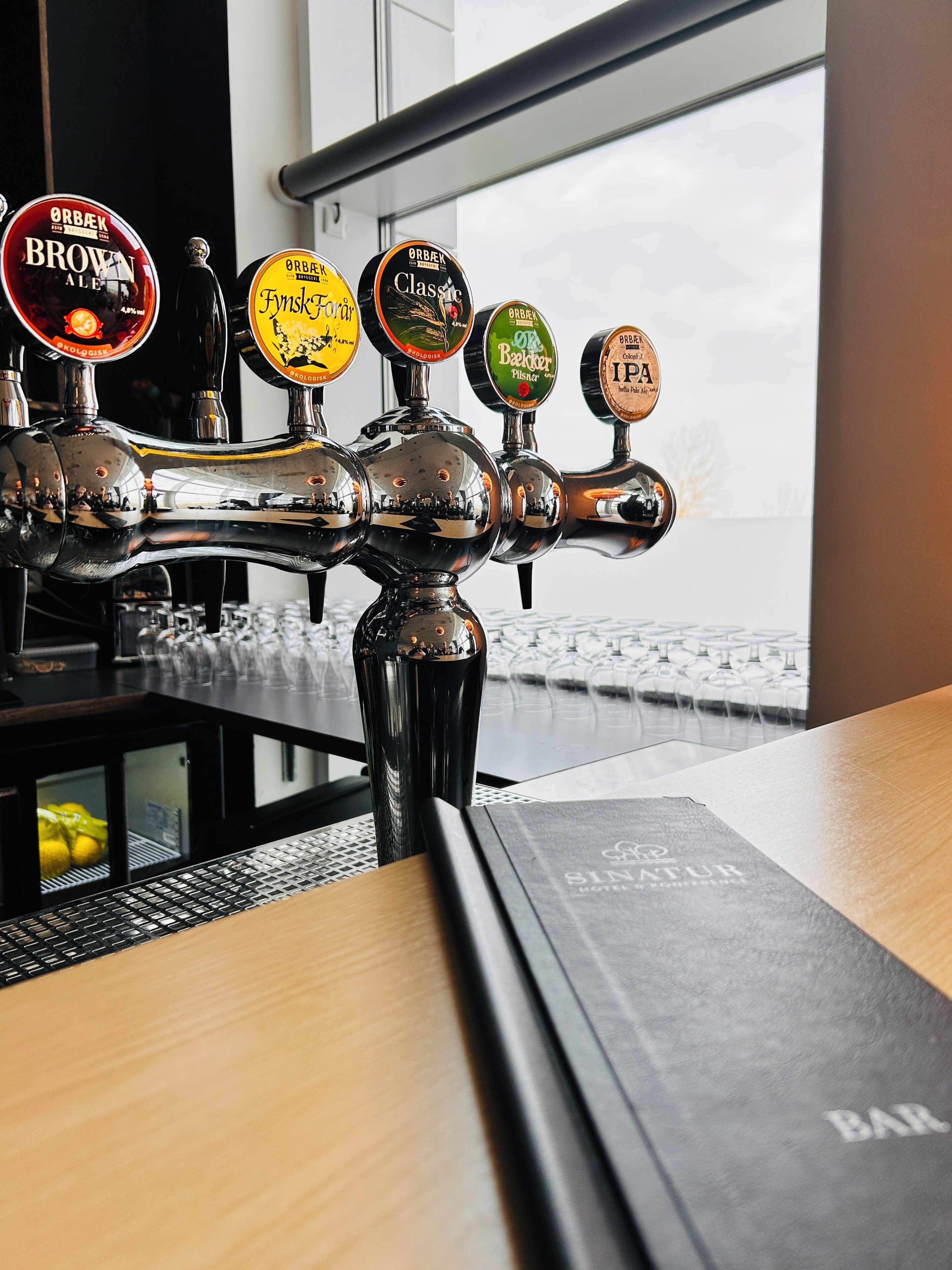 A bar area with multiple taps, a menu, and a view through the window.