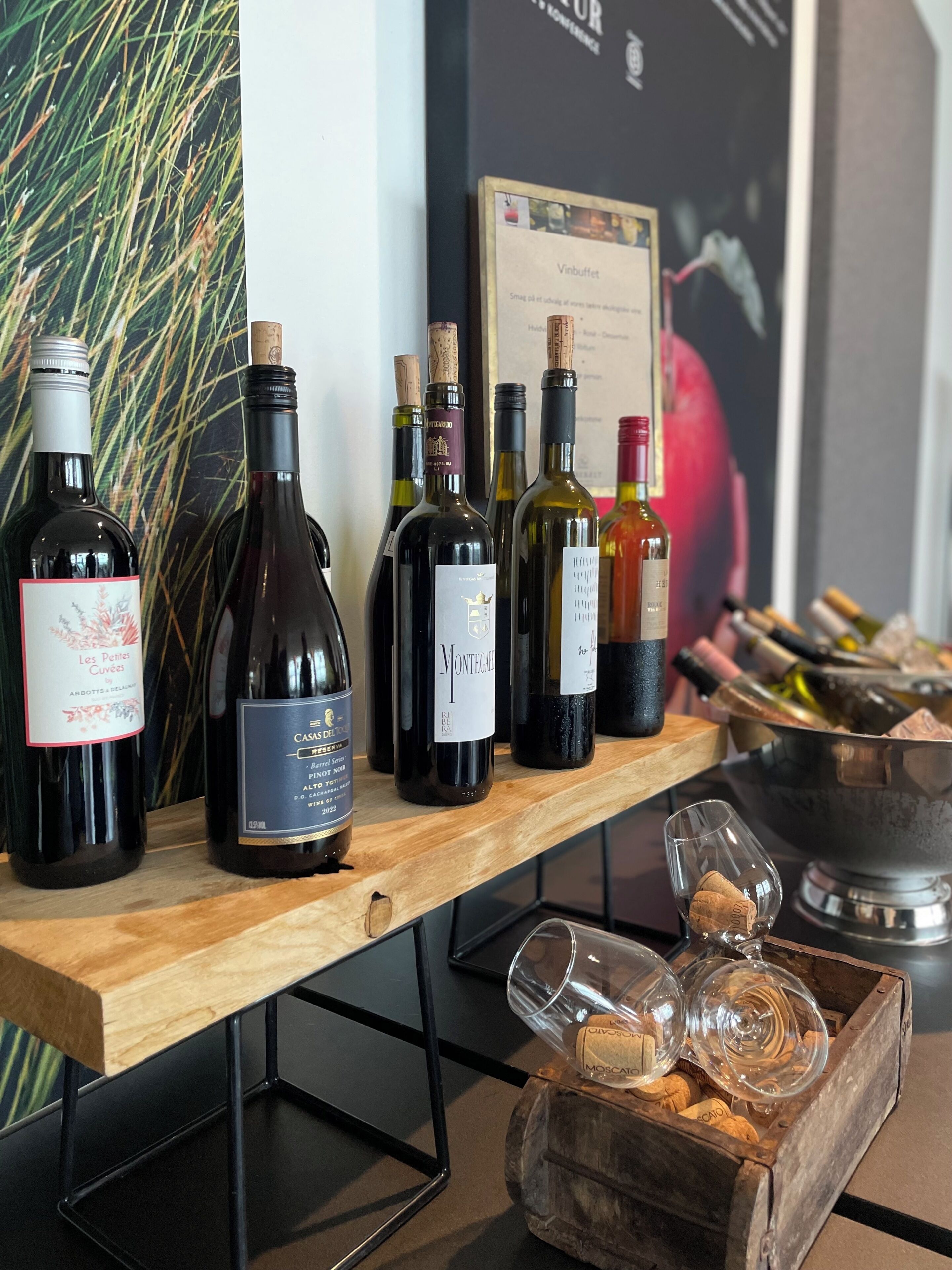A wine tasting setup with various bottles and glasses on a wooden table.
