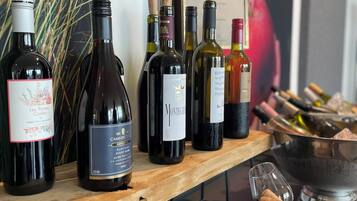 A wine tasting setup with various bottles and glasses on a wooden table.