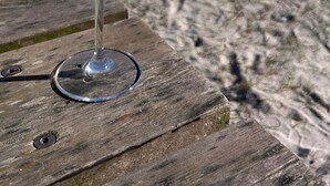 Un vaso de una bebida de color claro con pajita y una rodaja de limón sobre una superficie de madera.