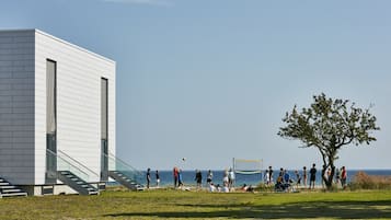 A modern building with a staircase leading to a balcony overlooking the sea.