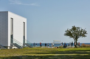 A modern building with a staircase leading to a balcony overlooking the sea.