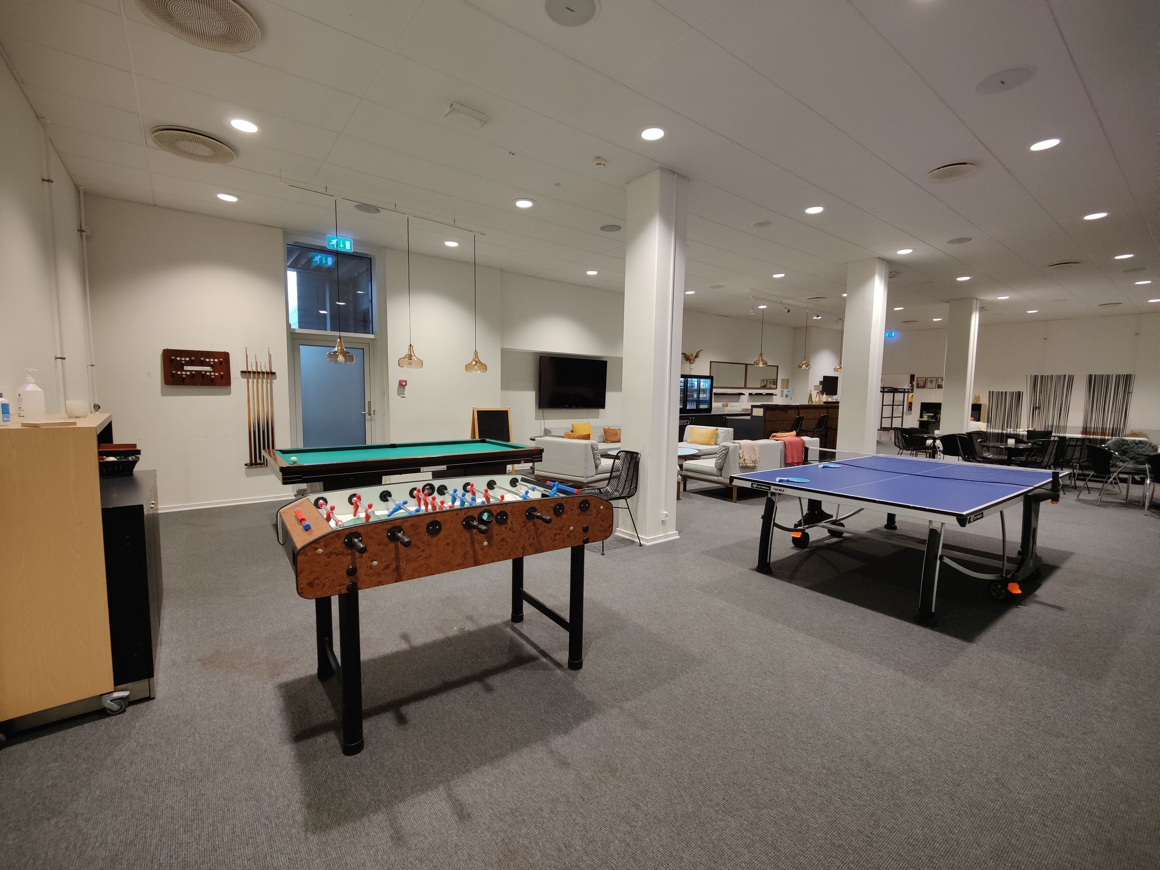 Ett rum med ett fotbollsspel, ett bordtennisbord och ett biljardbord.