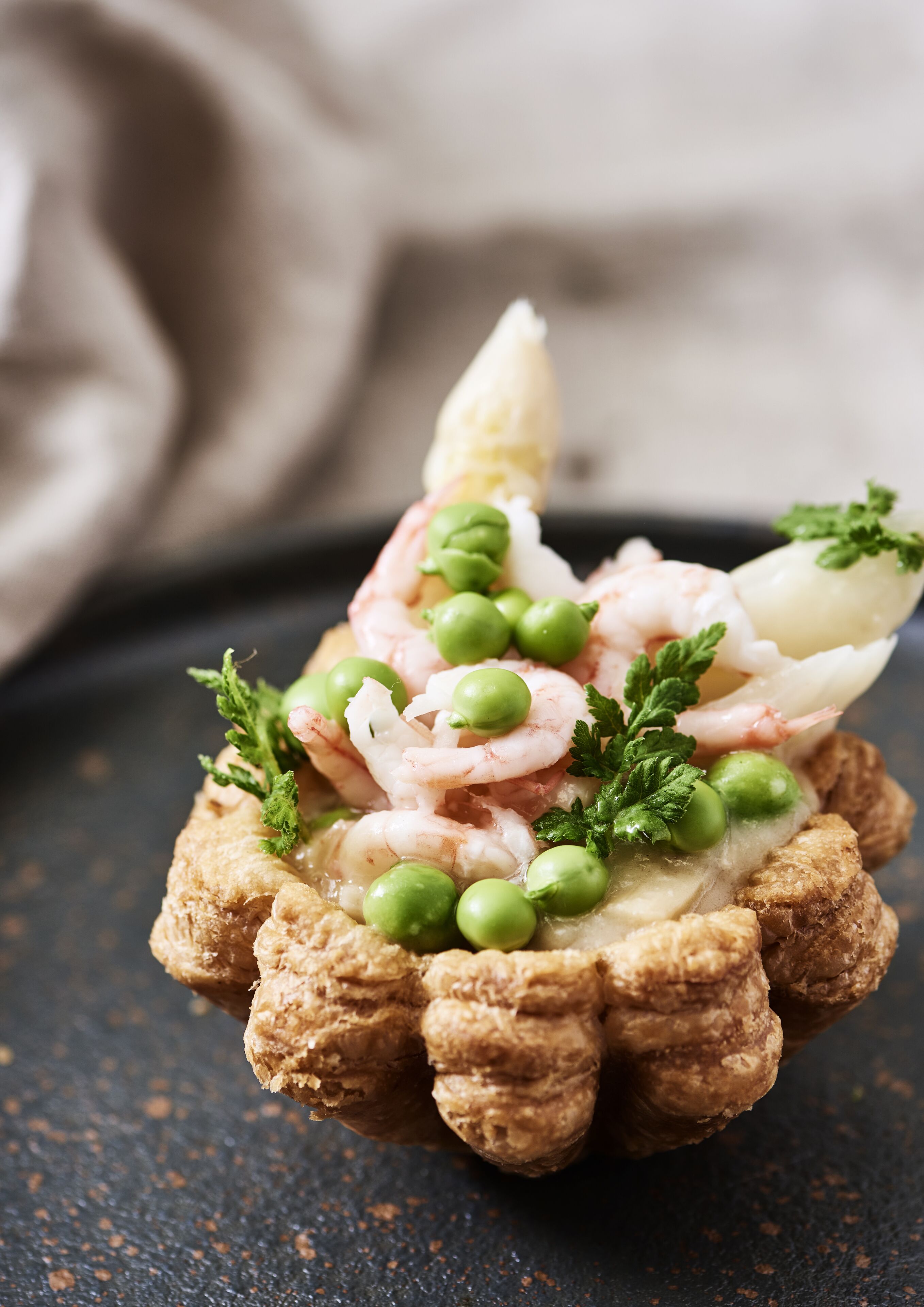 Un plato con camarones, guisantes y hierbas sobre una base de pan.