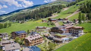 A mountain resort with multiple chalet-style buildings, ski slopes, and a clear blue sky. - Berghotel (Sesto)