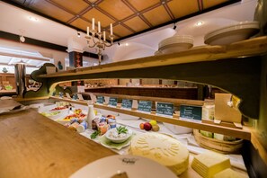 A cheese and deli counter with various cheeses, fruits, and condiments. - Berghotel (Sesto)