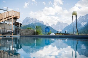 A mountain resort with a swimming pool, wooden deck, and mountain views. - Berghotel (Sesto)