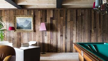 A wooden-paneled room with a pool table, a framed painting, and a lamp.