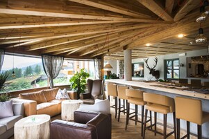 Amplia sala de estar con techo de madera, un sofá, una mesa de centro y una barra con taburetes.