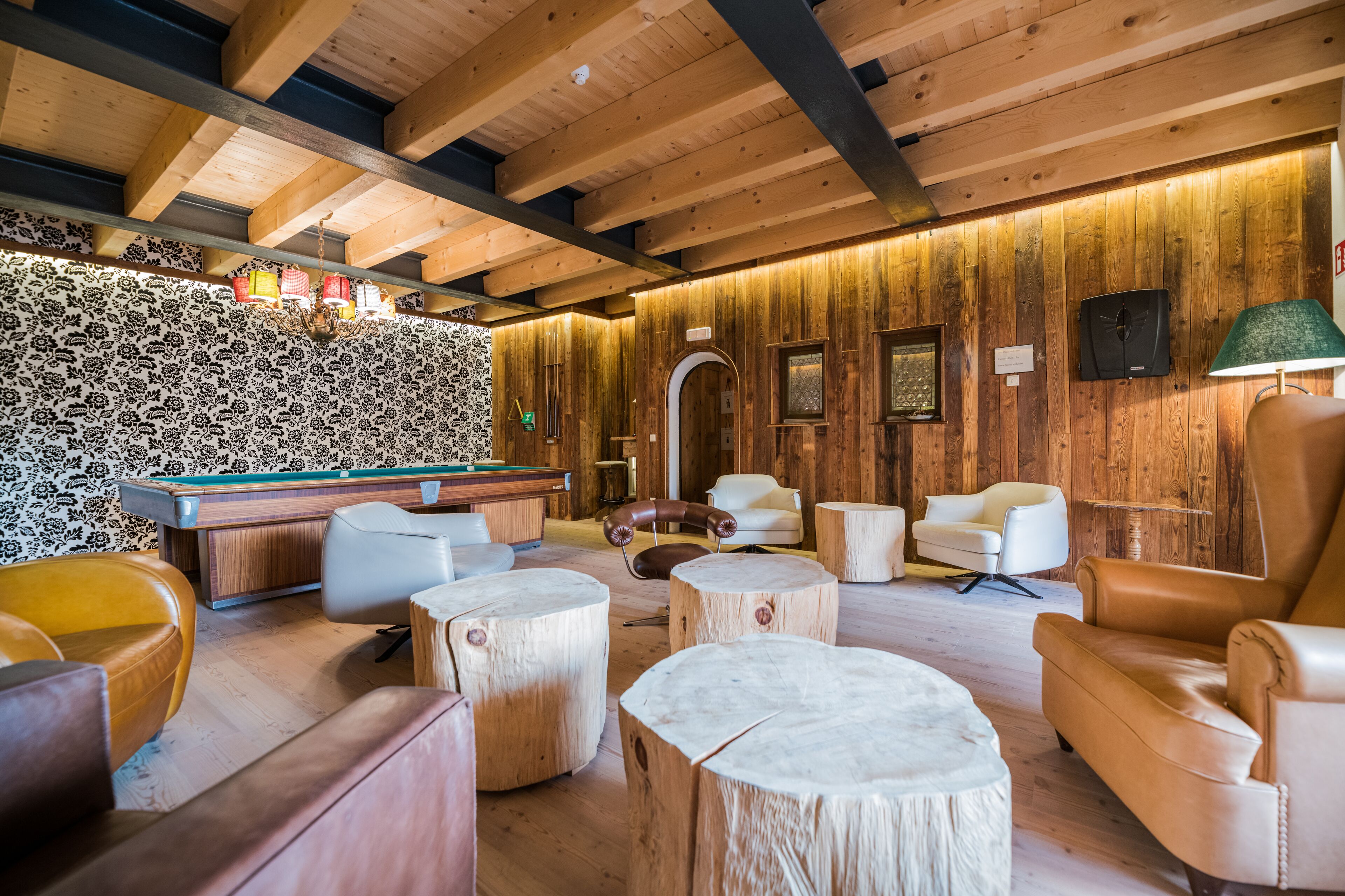 Ein Holzinterieur mit Poolbillardtisch, Ledersesseln und einer Billardausstattung.
