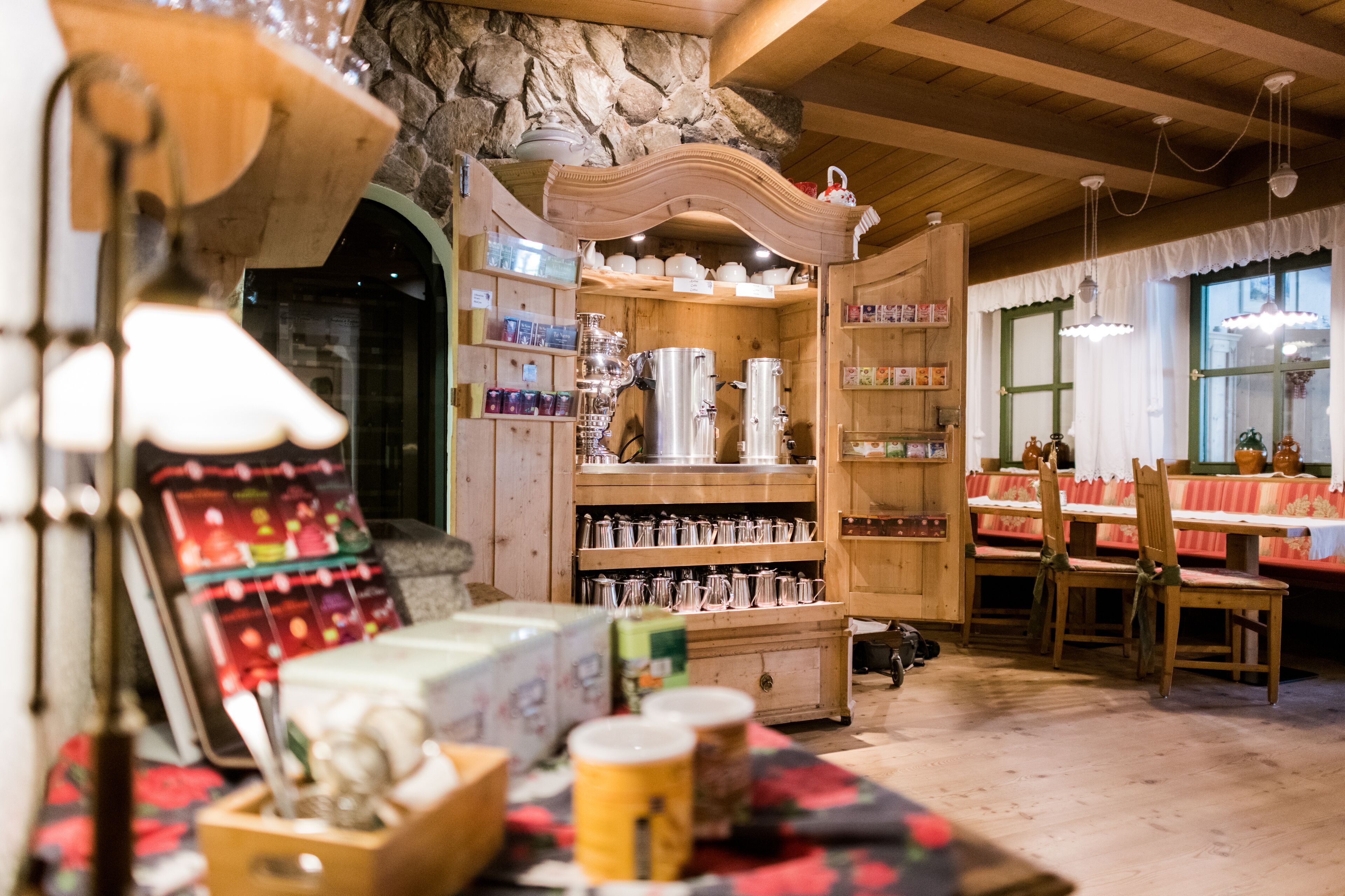 A cozy interior with wooden shelves displaying various kitchenware and a dining area with benches and chairs.
