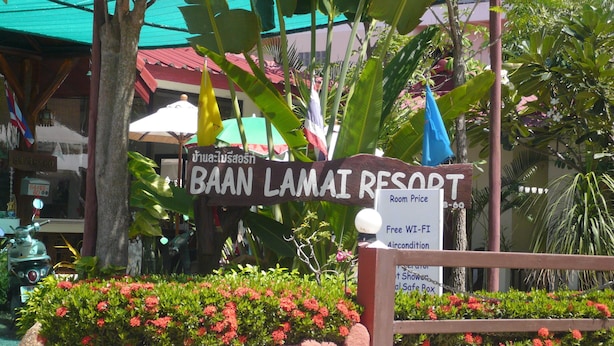 A sign for BAAN LAMAI RESORT with amenities listed including free Wi-Fi, air conditioning, and a shower.
