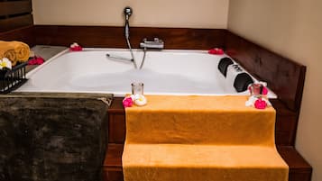 Et badeværelse med badekar, en træbænk og et håndklædestativ.