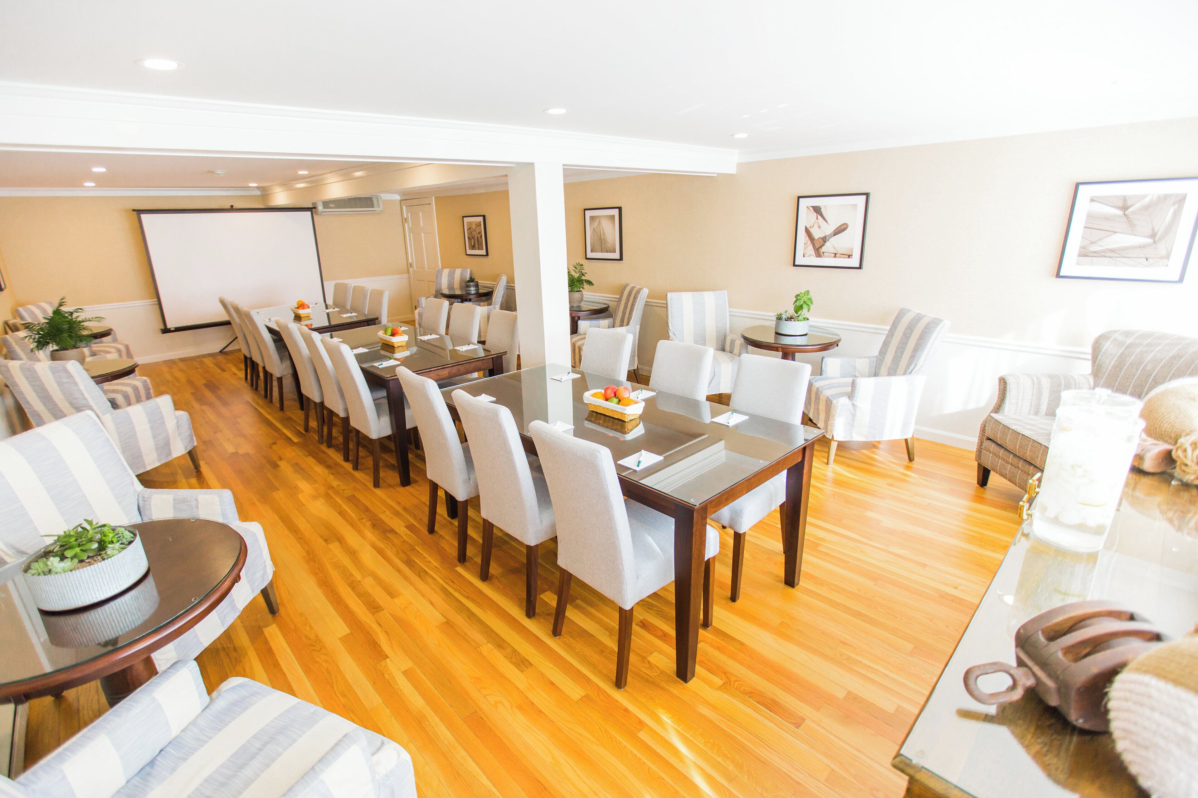 A spacious dining area with a long table, multiple chairs, and a projector screen.
