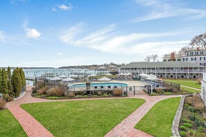A waterfront hotel with a pool, outdoor seating, and a view of the water.
