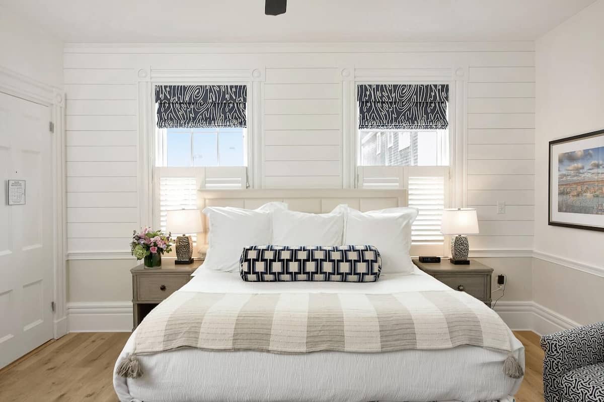 Un dormitorio ordenado con una cama grande, dos mesitas de noche y un cuadro enmarcado en la pared.