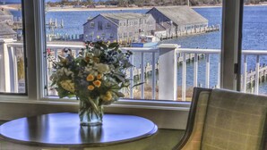 A view from a window overlooking a dock with a boat, a pier, and a building with a blue roof. - The Harborside Inn (Edgartown)
