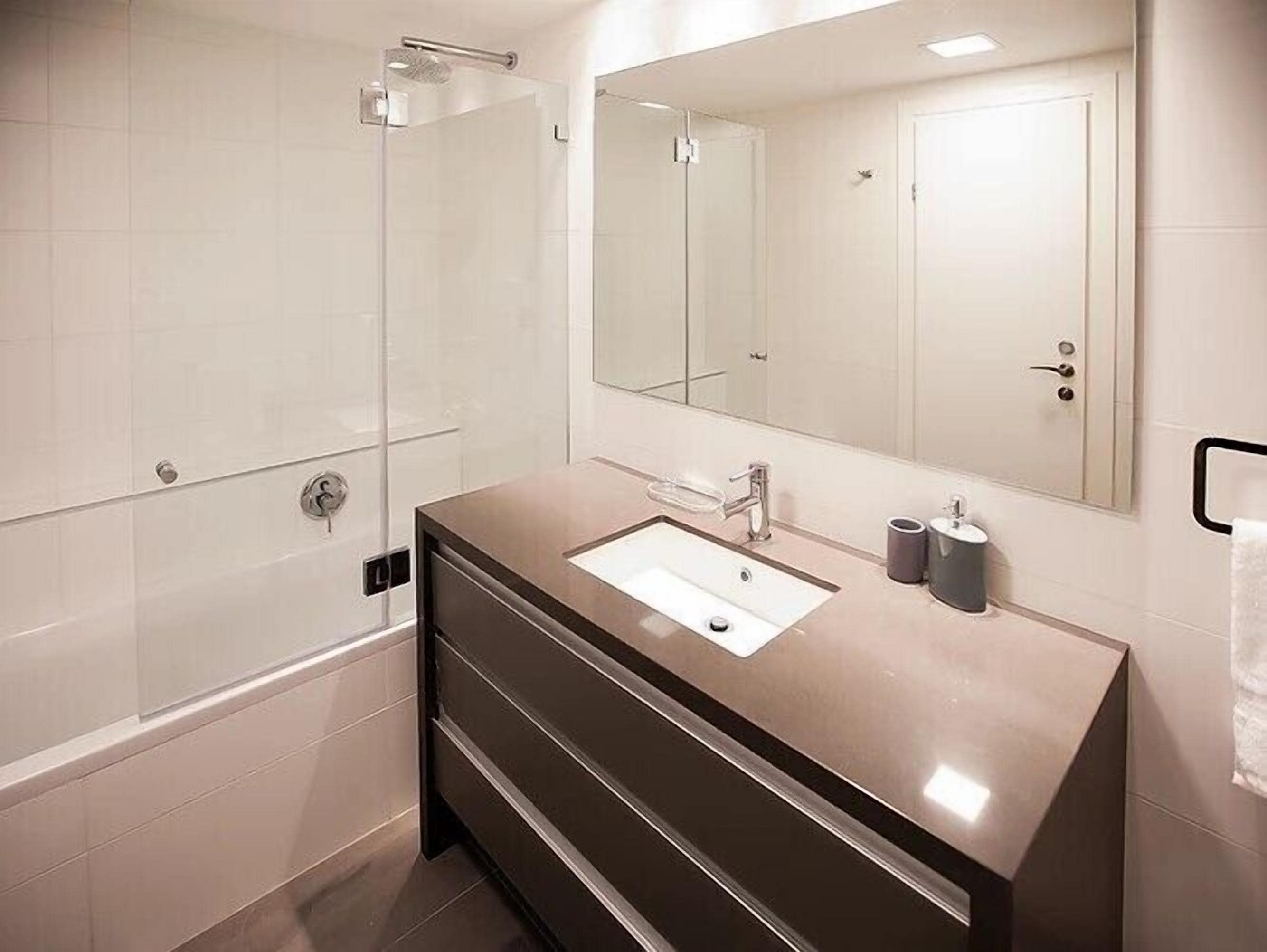 Un baño moderno con un espejo grande, un lavabo y una ducha.