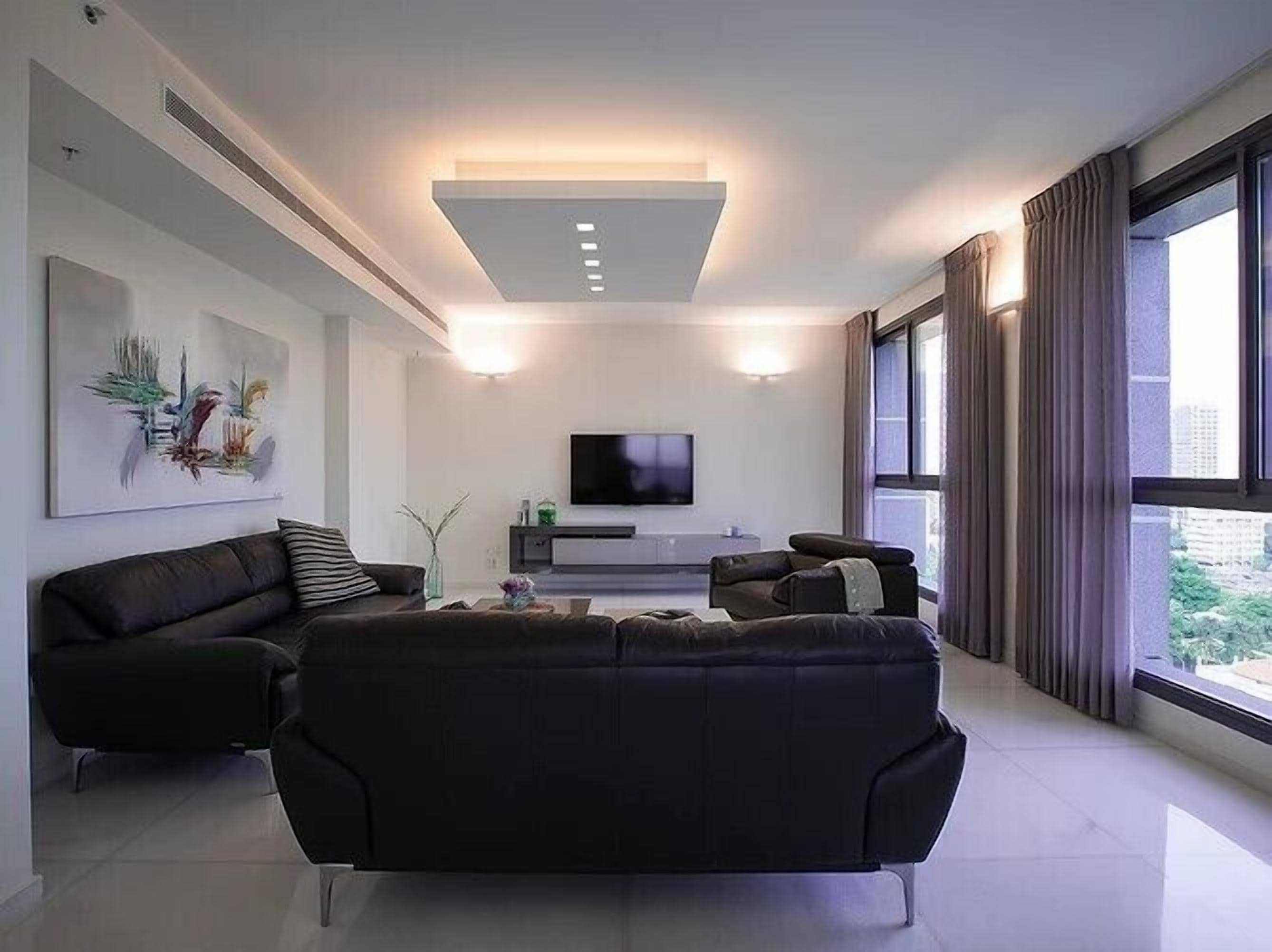 A modern living room with a sectional sofa, a flat-screen TV, and a large window with curtains.