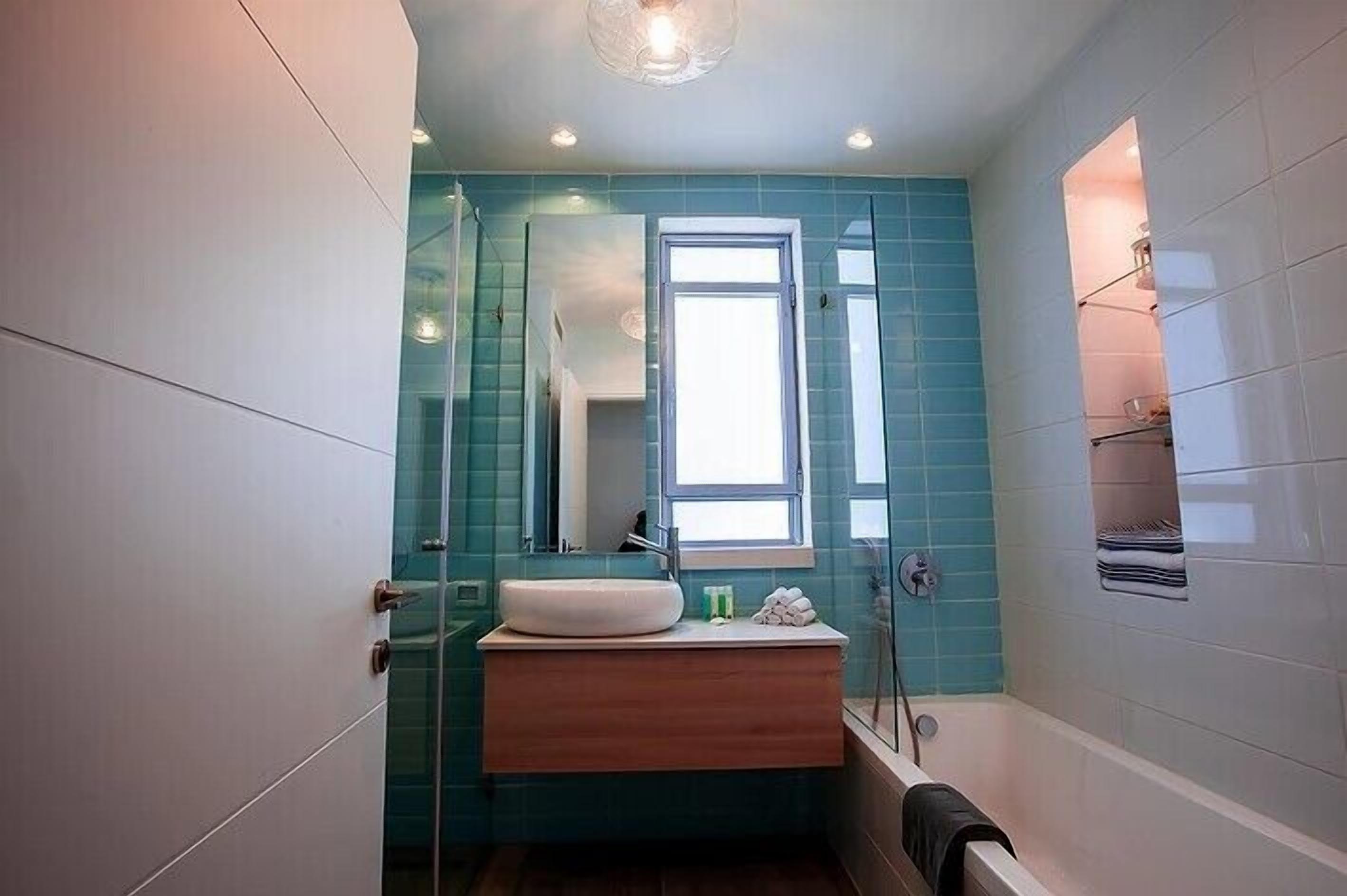 Een moderne badkamer met een douchecabine van glas, een ingebouwd wastafelmeubel en een raam voor natuurlijk licht.