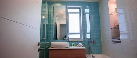 Een moderne badkamer met een douchecabine van glas, een ingebouwd wastafelmeubel en een raam voor natuurlijk licht.