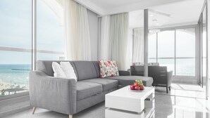 A modern living room with a grey sofa, white coffee table, and a view of the ocean. - Tel Aviv Home (Tel Aviv)