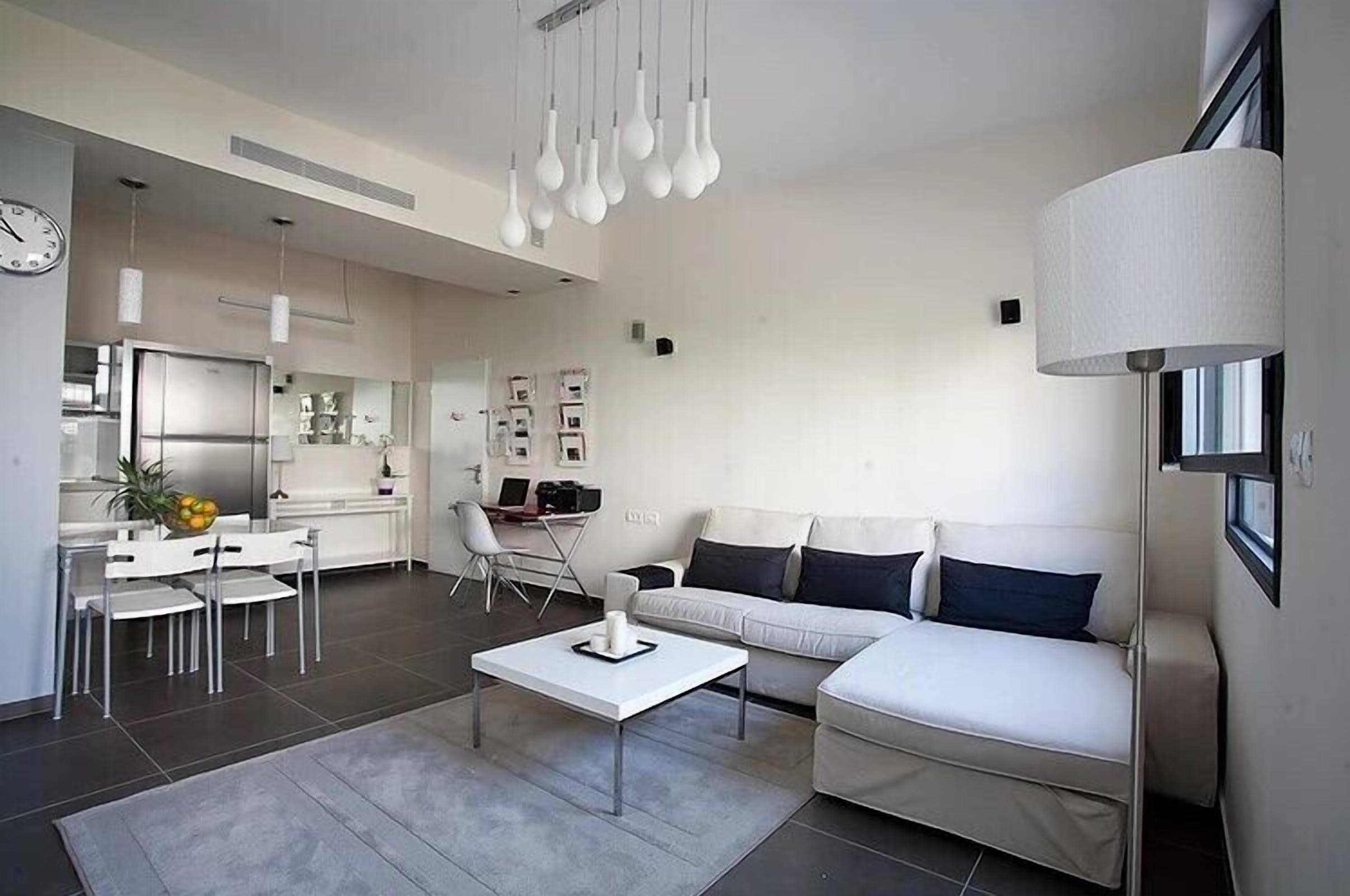 A modern living room with a white sofa, a coffee table, and a dining area with a white table and chairs.