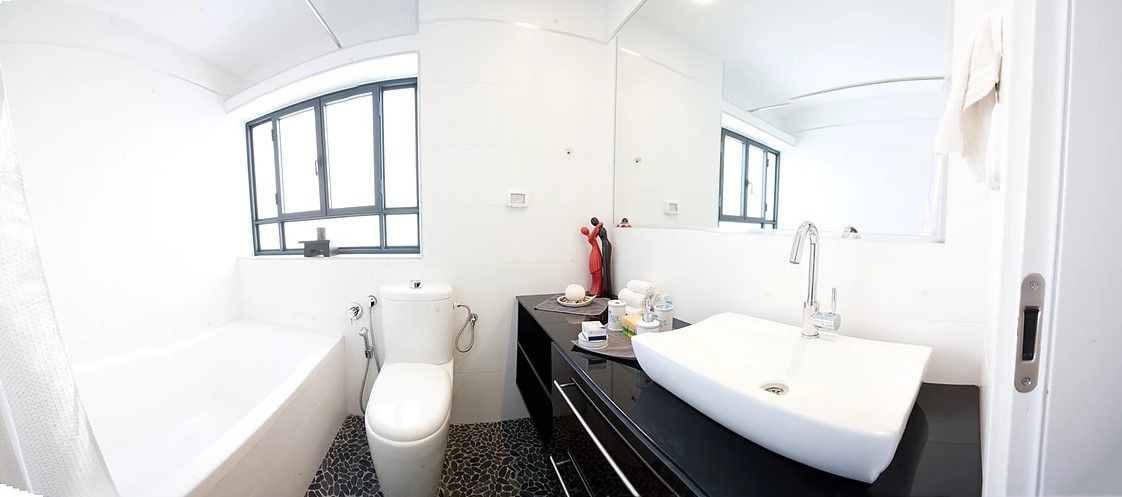 A modern bathroom with a bathtub, toilet, and a vanity with a sink and mirror.