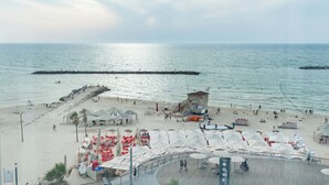 A beach with a lifeguard tower, umbrellas, and beach chairs. - Tel Aviv Home (Tel Aviv)