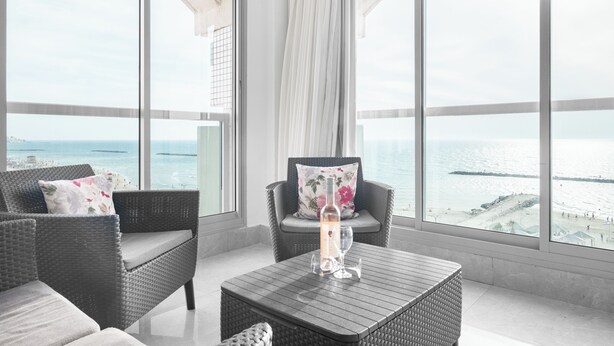 A balcony with wicker furniture, a glass table, and a candle. - Tel Aviv Home (Tel Aviv)