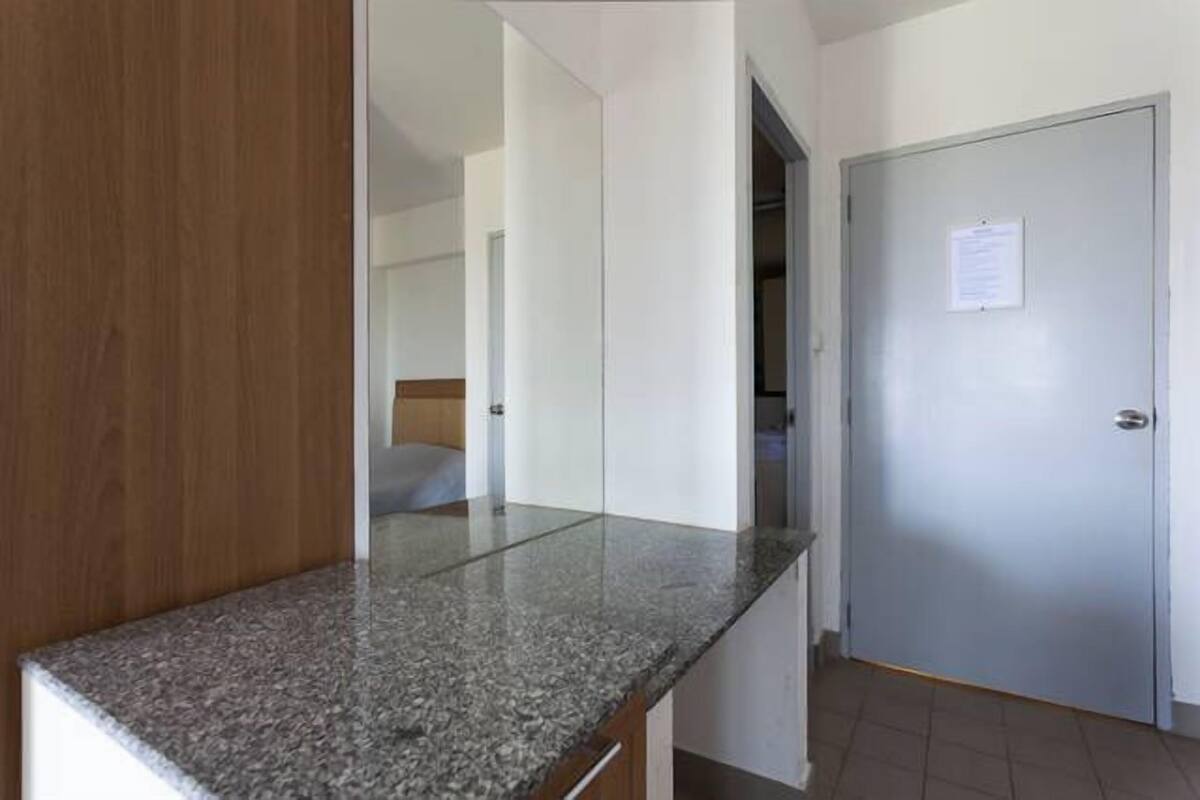 Un pasillo con encimera de granito, una puerta cerrada con un aviso y un panel de madera a la izquierda.