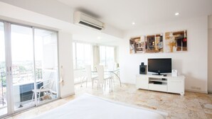 Una habitación de hotel moderna con una cama grande, televisión y balcón con vistas.