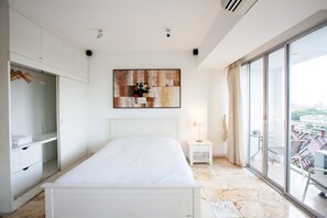 Een moderne slaapkamer met een groot bed, een garderobe, een nachtkastje en uitzicht op de stad door grote ramen.