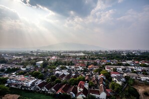 A residential area with houses, some greenery, and a mountain in the background. - Galare Thong Tower (Chiang Mai)