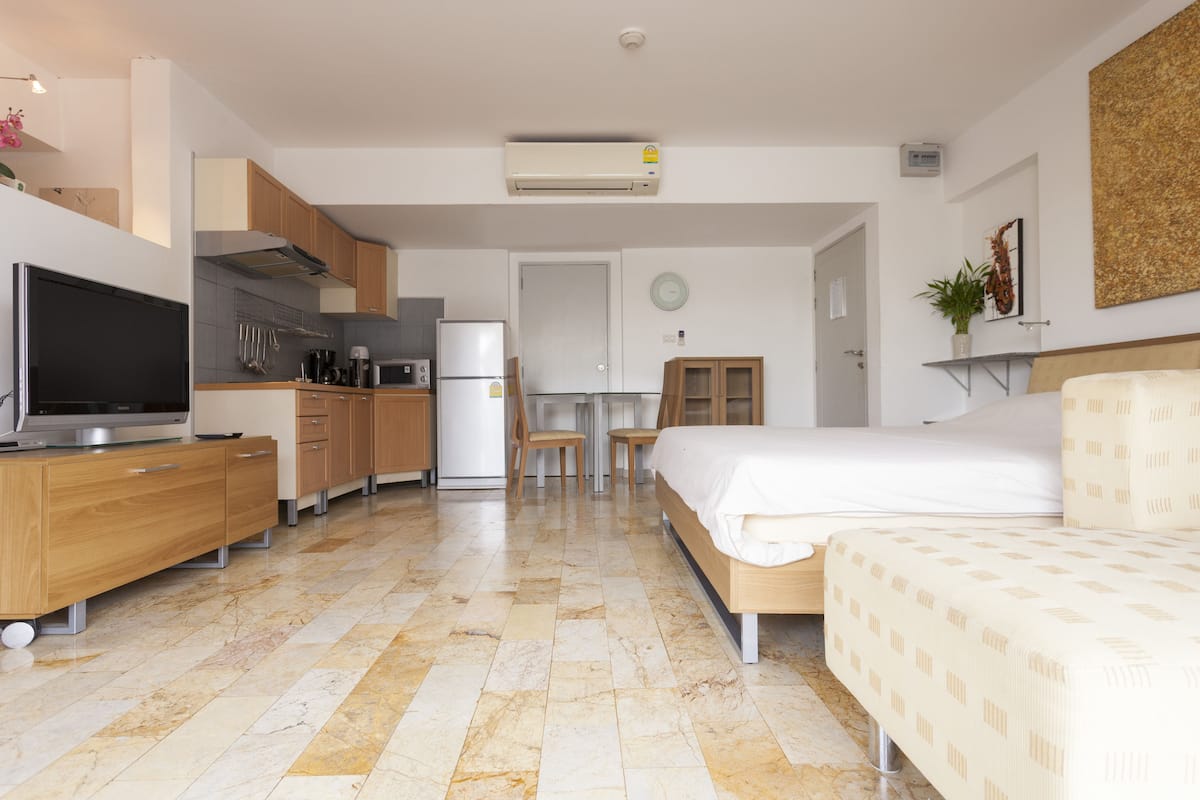 Una habitación de hotel moderna con cama, televisión, zona de cocina y mesa de comedor.