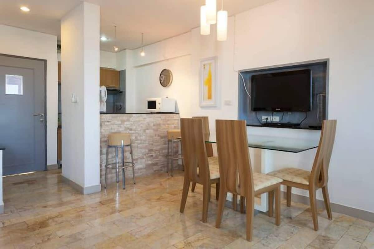 Una cocina moderna con salpicadero de piedra, microondas y televisor de pantalla plana montado en la pared.