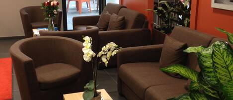A modern living room with brown sofas, a wooden coffee table, and a potted plant.