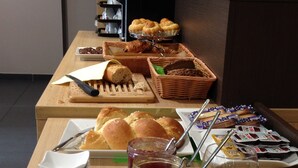 Una mesa de buffet con diversas opciones de comida, como pan, pasteles y salsas.