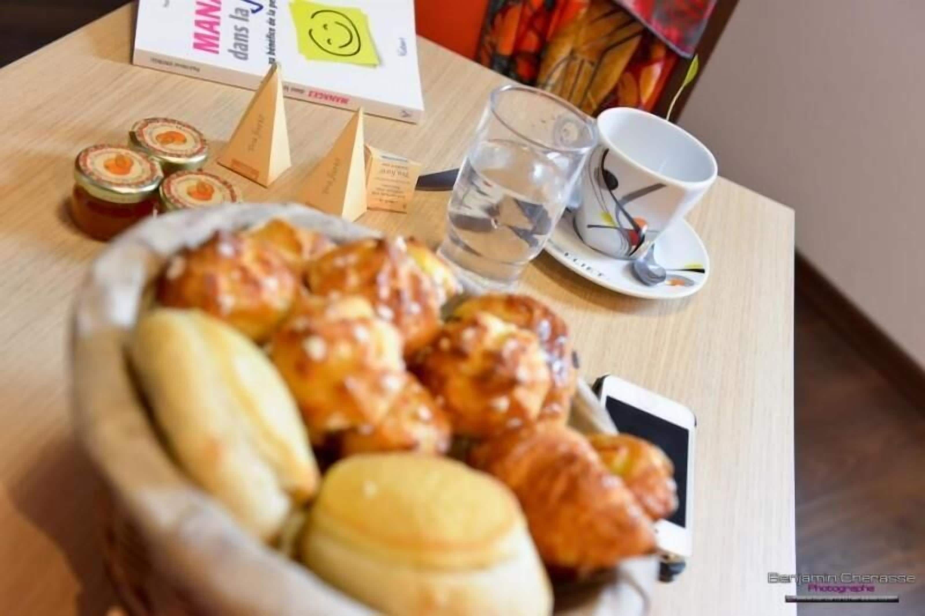 Una mesa con una cesta de pasteles, un vaso de agua, una taza y un libro titulado 'MANIA'.