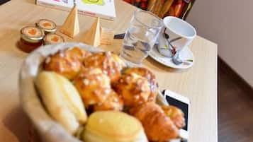 Een tafel met een mand gebakjes, een glas water, een beker en een boek getiteld 'MANIA'.