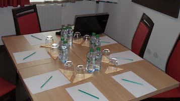 A conference room with a whiteboard, a TV screen displaying 'WELCOME', and a table set with water bottles and notepads.
