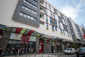 Ein mehrstöckiges Hotel mit modernem Design, das eine auffällige Eingangspartei mit Glasüren und einer roten Markise bietet.